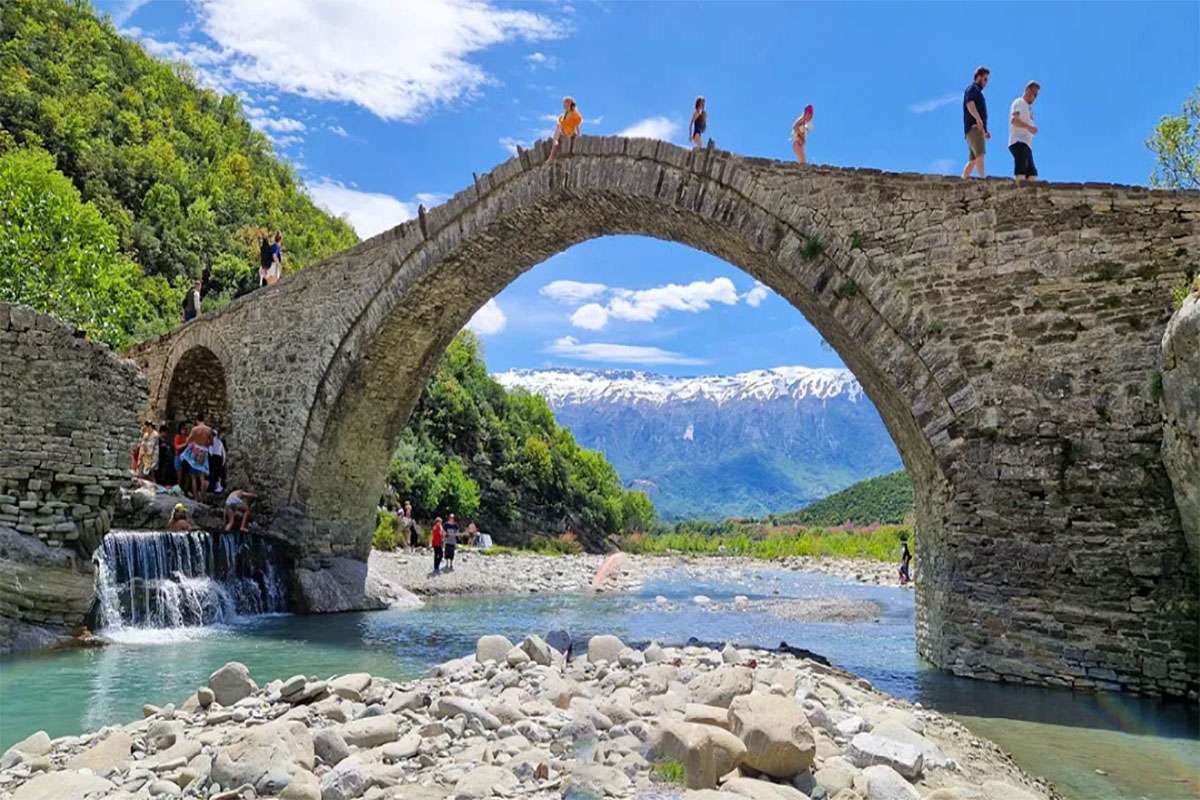 Il ponte di Benje con dei turisti che lo attraversano. sotto di loro il fiume calmo, in una giornata limpida